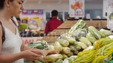 年轻女子在超市购物，健康食品，玉米在市场，超市。 选择食物
